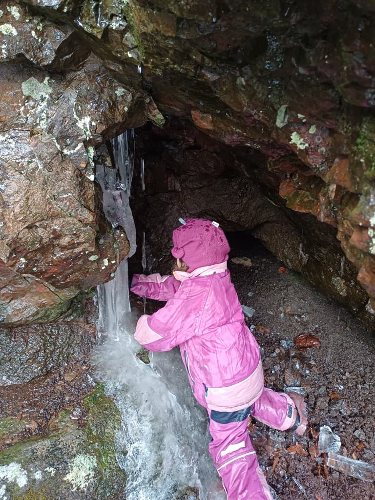 Barn som utforsker en hule i naturen